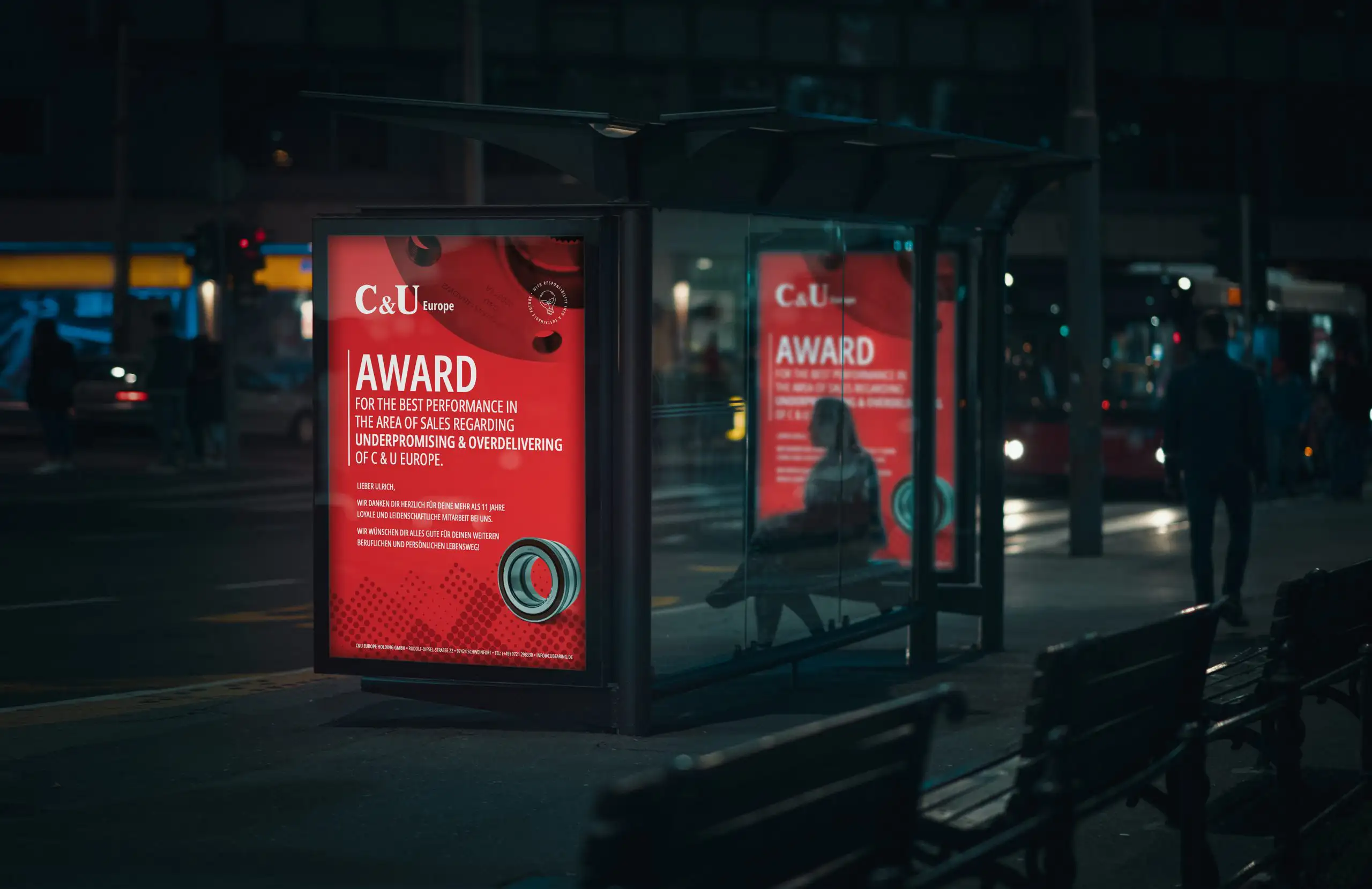 Zwei rote Werbeplakate der Firma C&U Europe an einer Bushaltestelle